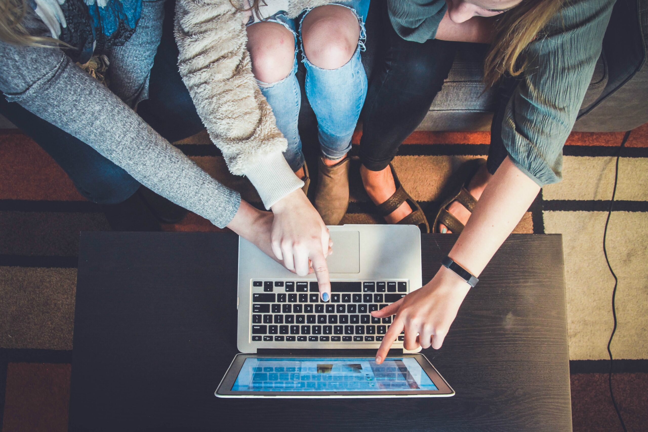 4 people with macbook pro touching it with hands